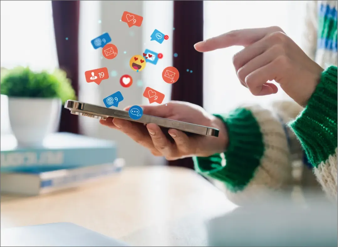 A person holding a smartphone with floating social media icons representing likes, shares, and comments, symbolizing digital engagement.