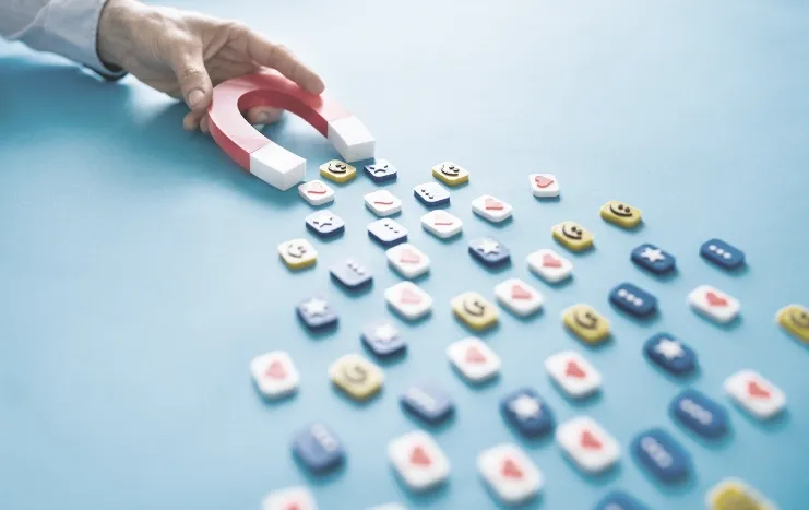 A hand holding a magnet attracting social media icons